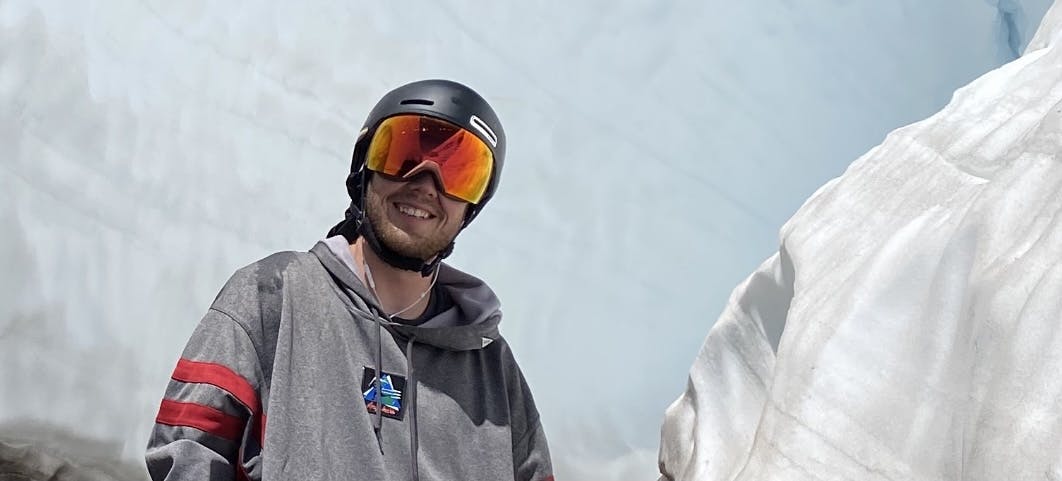 A skier wearing the Smith Skyline Goggles with a helmet. There is snow in the background. 