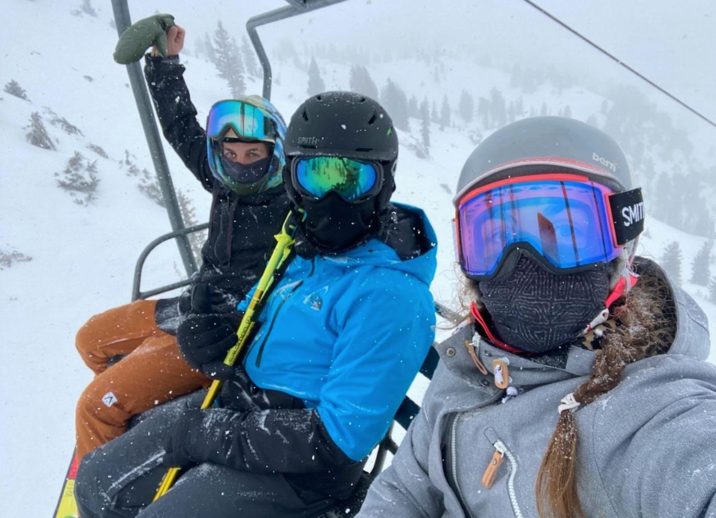 Three people sitting on a chairlift at a ski resort.