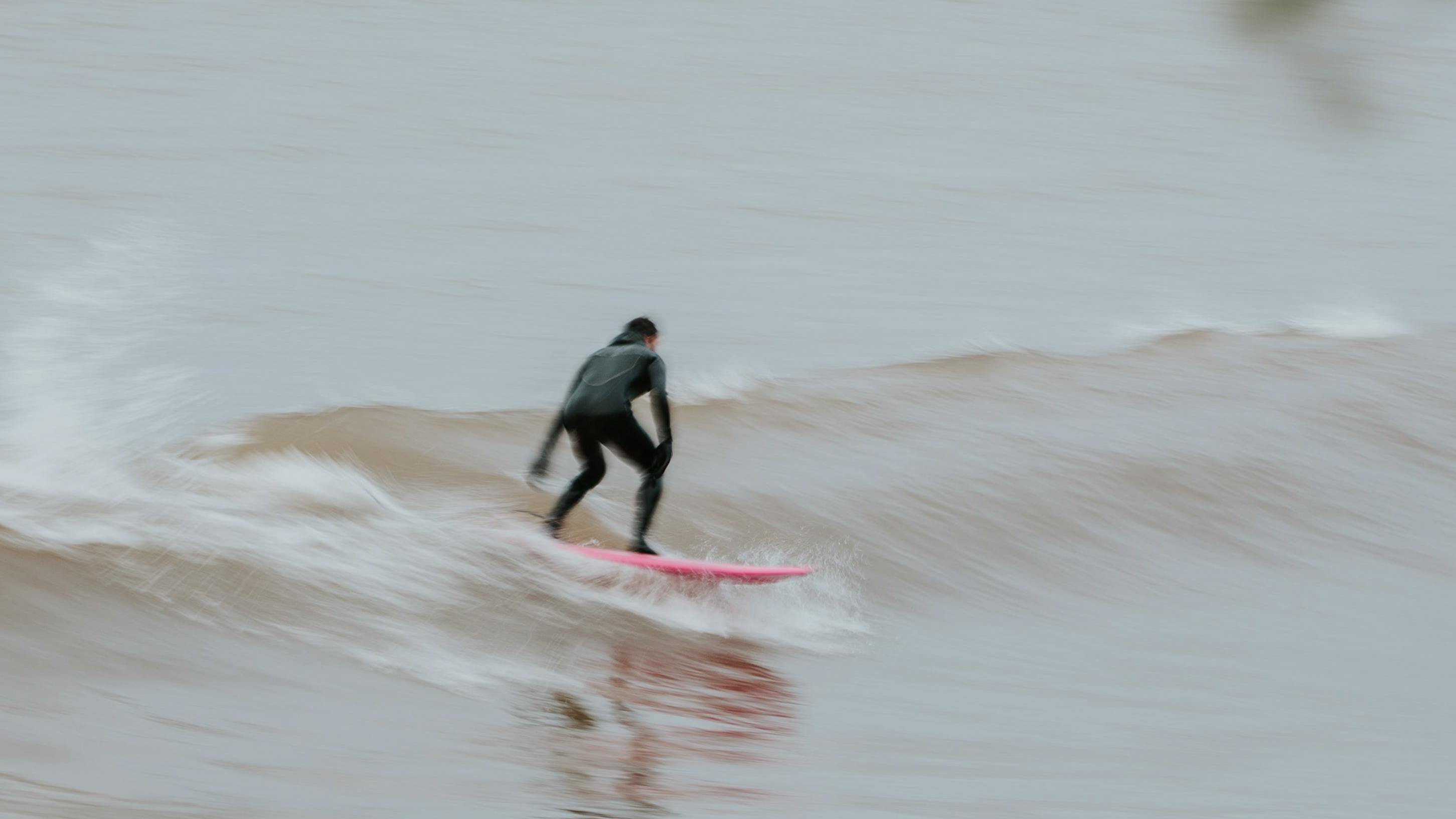 Surfer braving the cold winter conditions before winter arrives for surfing the ski resorts.