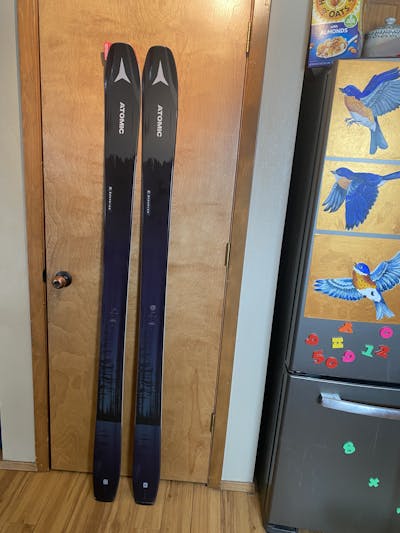 The Atomic Maverick 100 TI skis leaning against a door. 