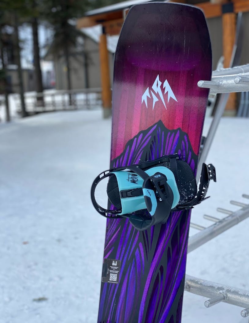 The Jones Airheart 2.0 Snowboard 2023 leaning against a ski rack. 