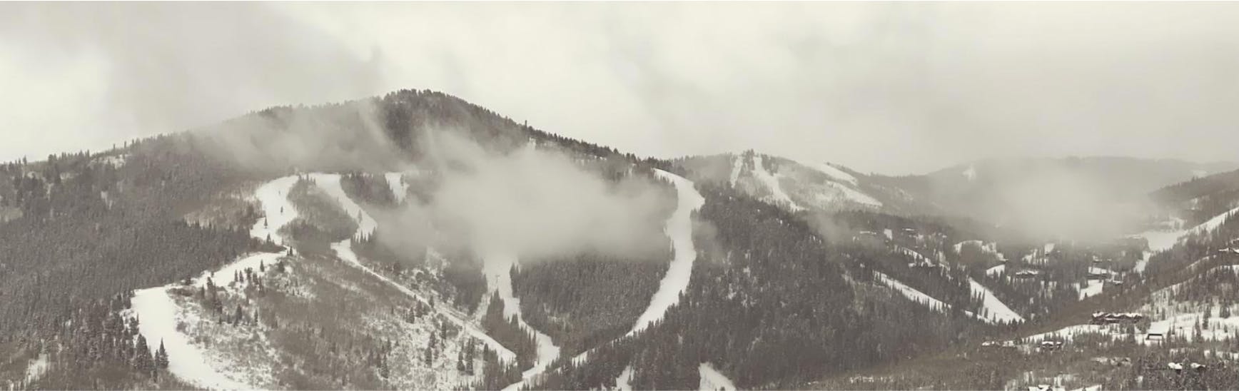 A black and white photo of misty clouds over a mountain. 