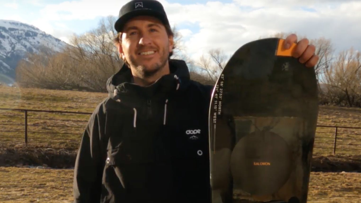 A man standing with the 2023 Salomon Super 8 Snowboard.