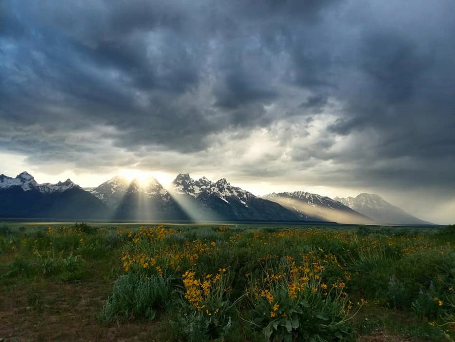 Sun streaming through clouds over mountains in Grand Teton National Park