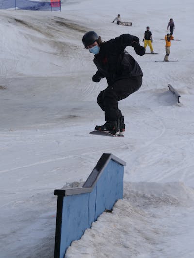 A snowboarder catches air over a rail.