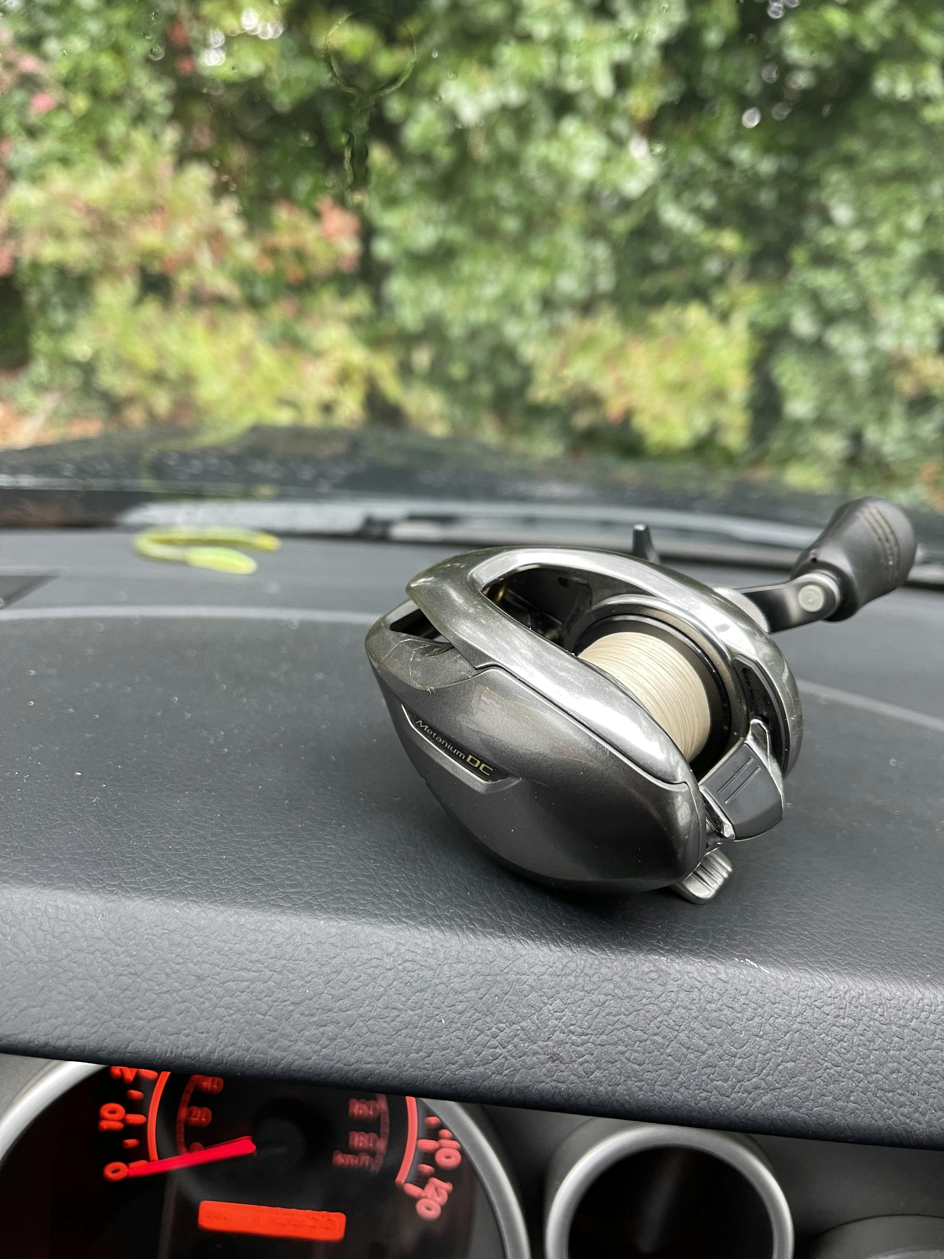 The Shimano Metanium DC Low Profile Baitcasting Reel laying on the dashboard of a car. 