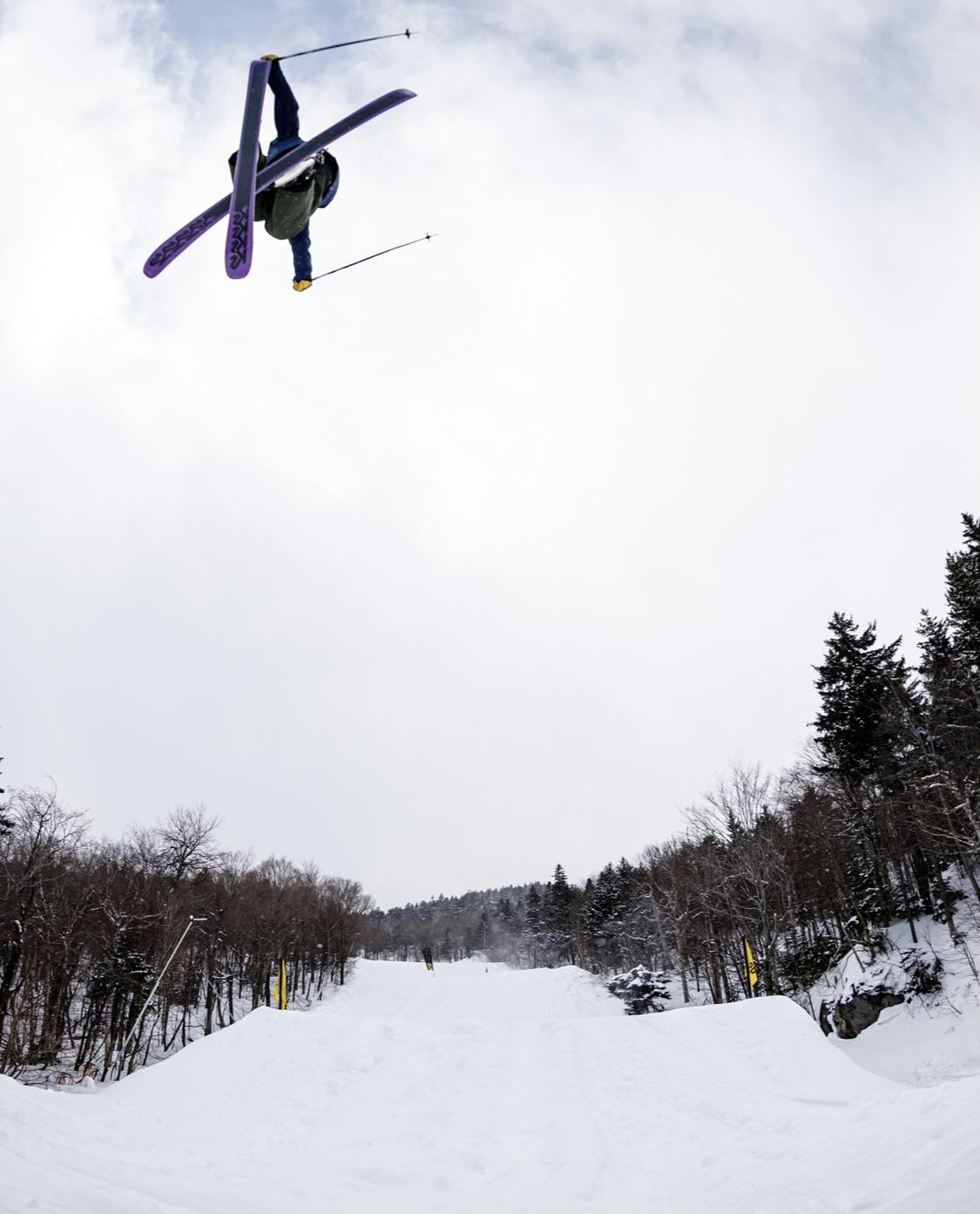 A skier gets air off a jump and grabs the tail of his ski.