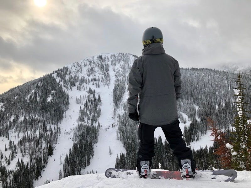 Man in full snowboarding gear, at the top of a snowy mountain
