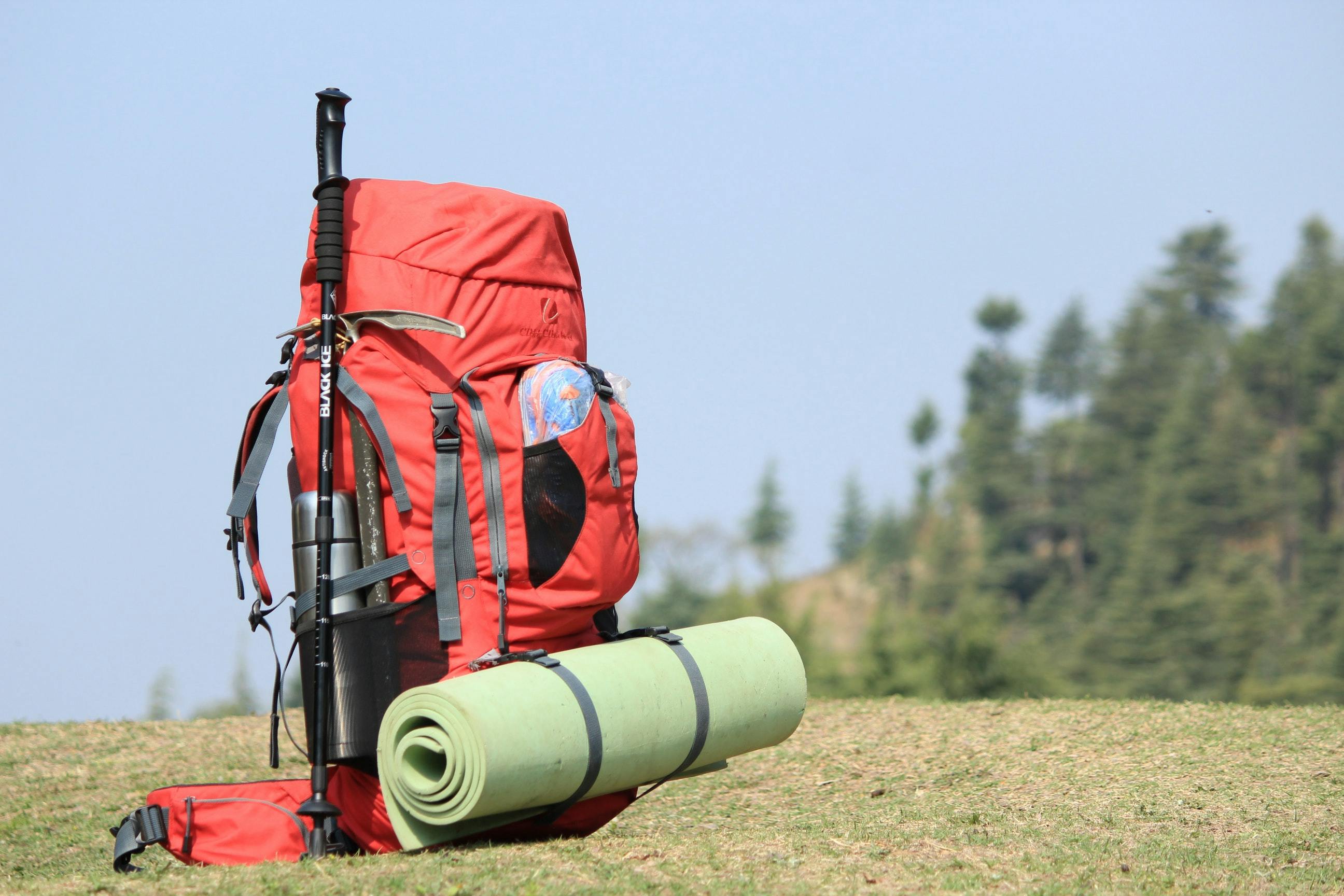 A light green sleeping pad attached to the outside of a bright red backpack