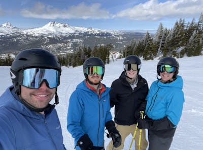 Four people standing at a ski resort. 