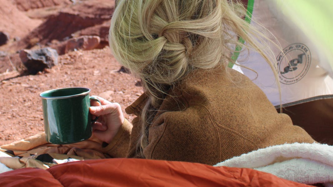 A woman holding a cup inside a tent. 