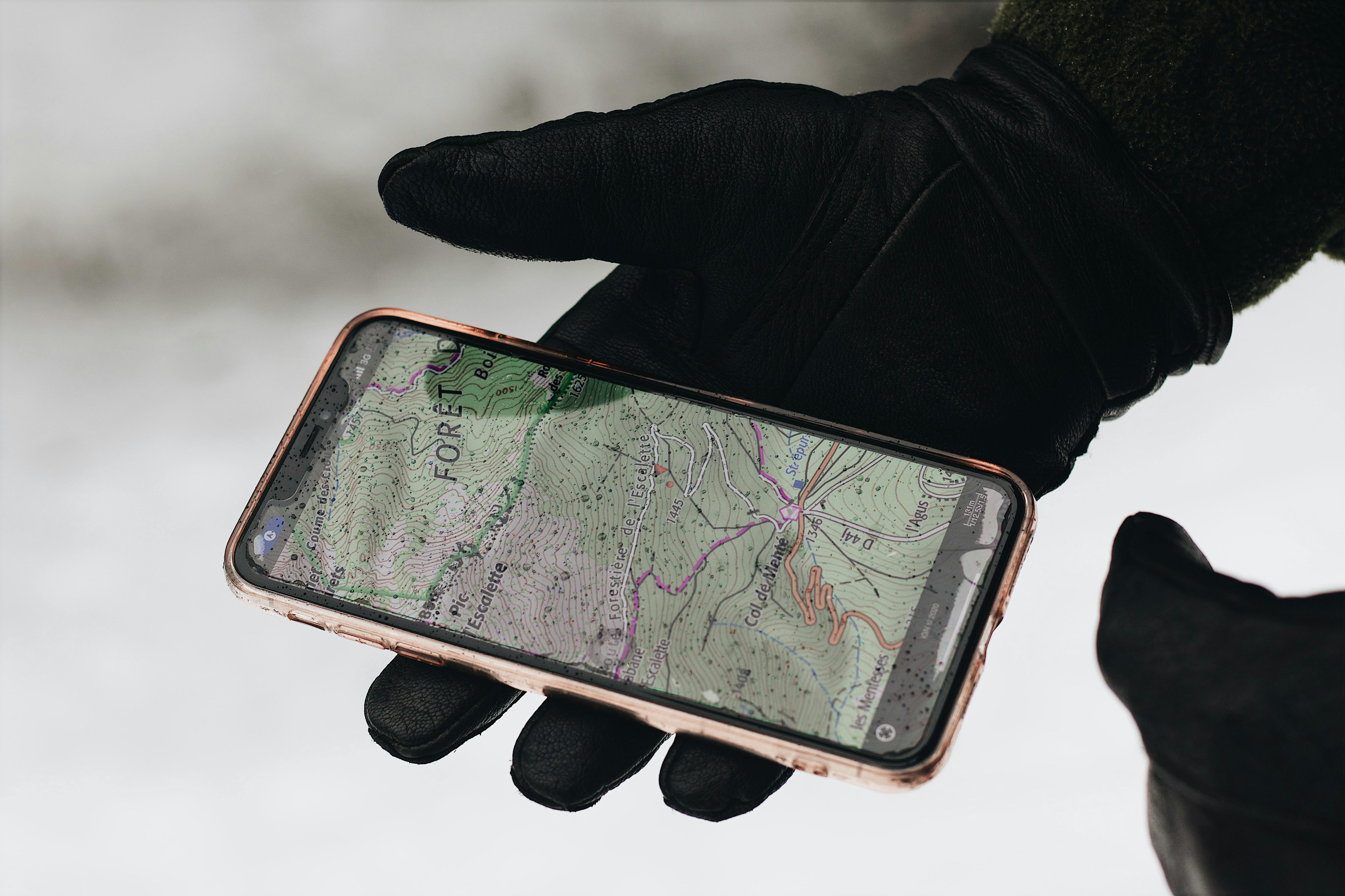 Gloved hands holding a phone with a map.