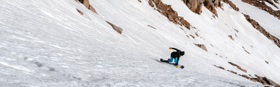 A snowboarder makes a turn on icy snow