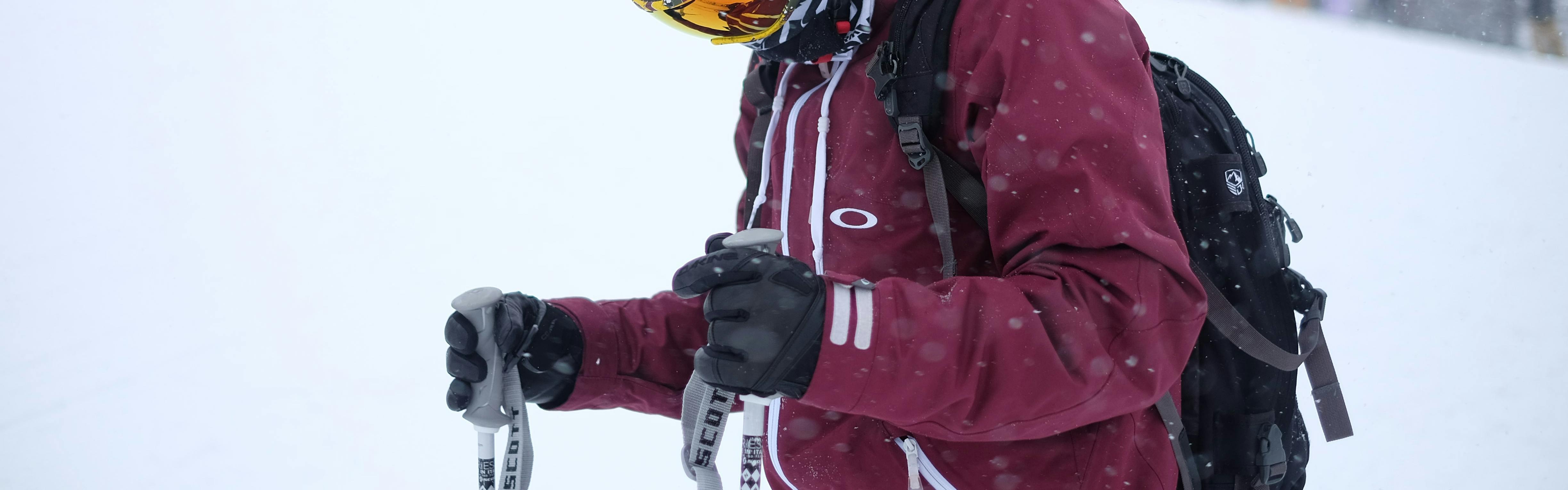 A skier holding his poles with his gloved hands. 