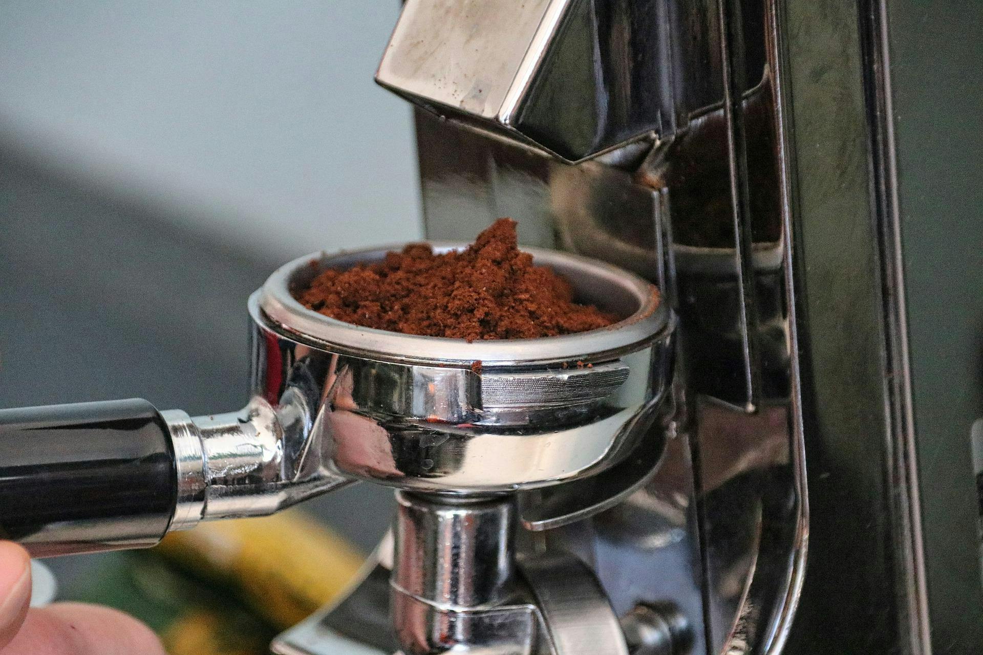Someone collects ground coffee into an espresso portafilter.