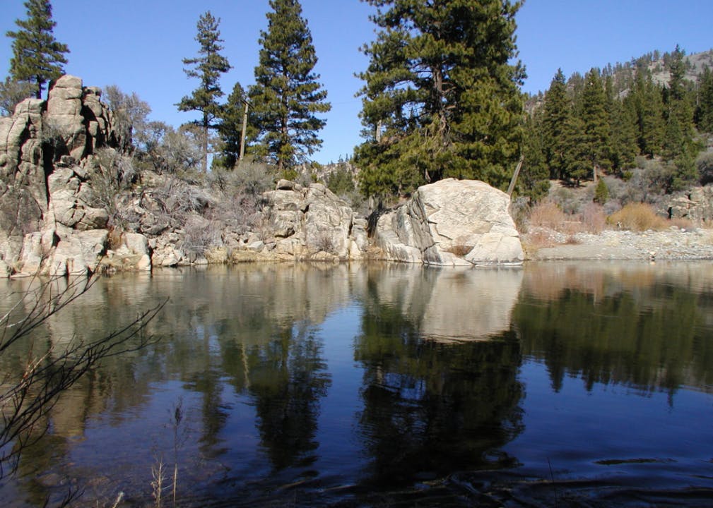 A calm lake lined with granite boulders and trees