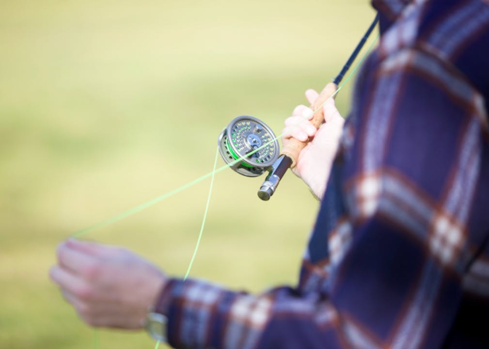 Closeup on a fisherman holding a fly reel and fly line