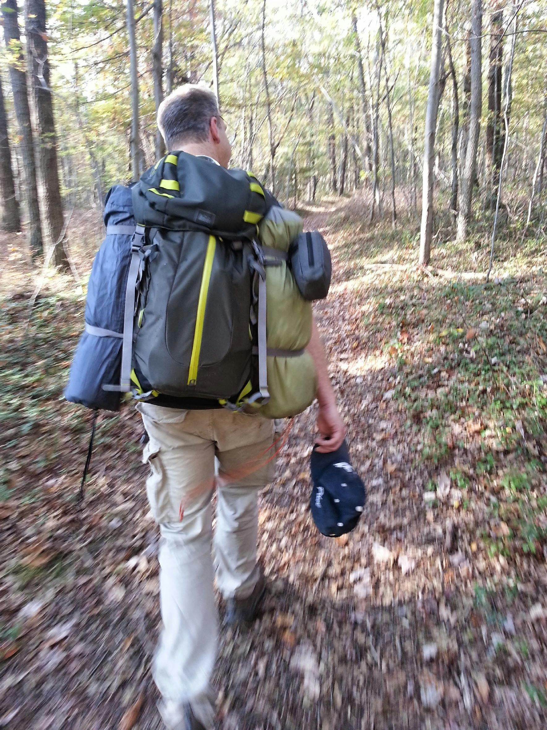 A man with a large backpack walking down a trail.