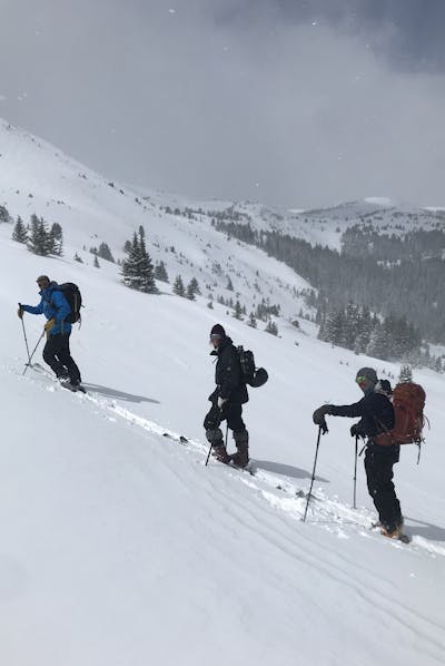 Three skiers walking uphill. 