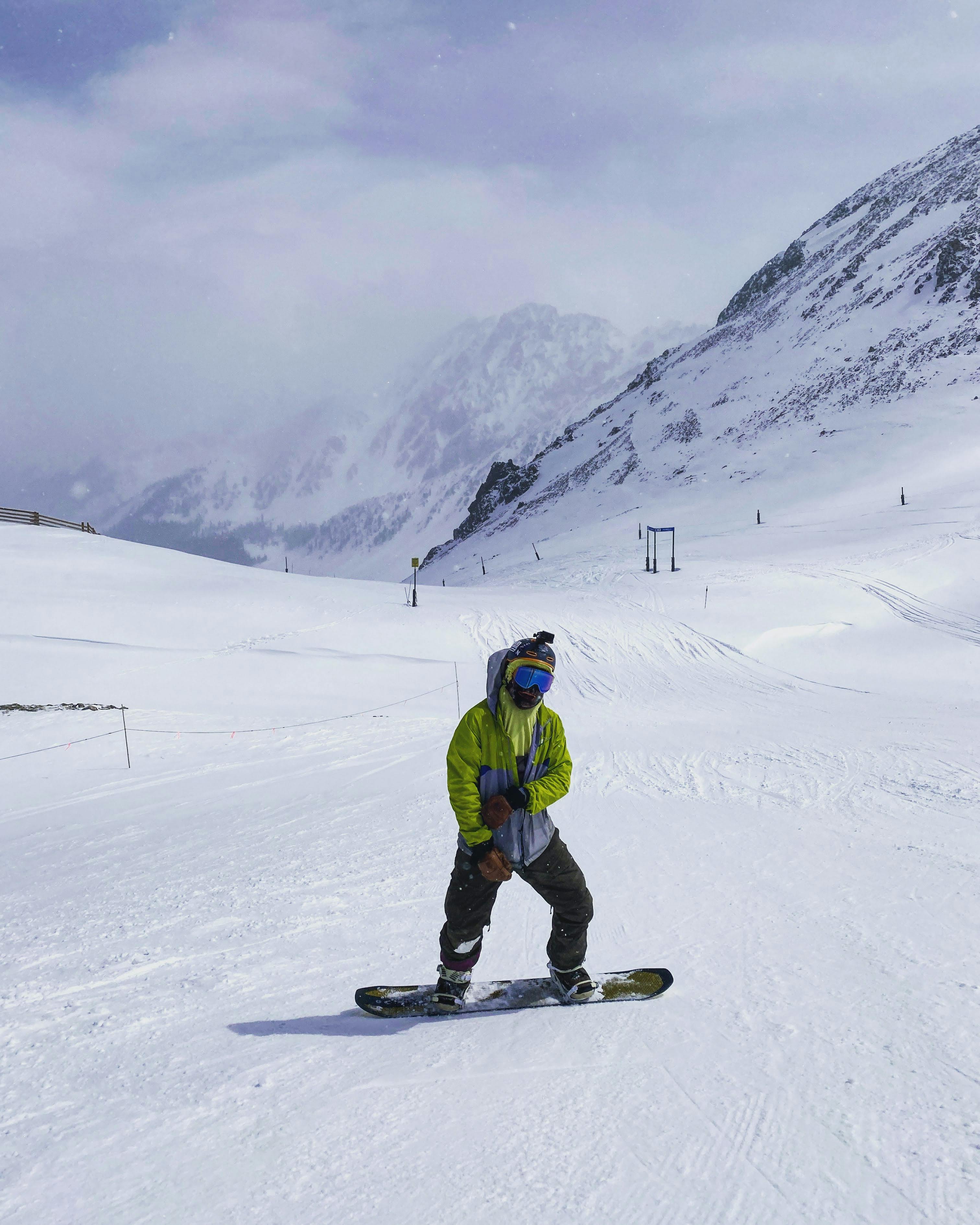 The author stands on his board on an empty, snowy hill. Dramatic, foggy peaks are in the background. 
