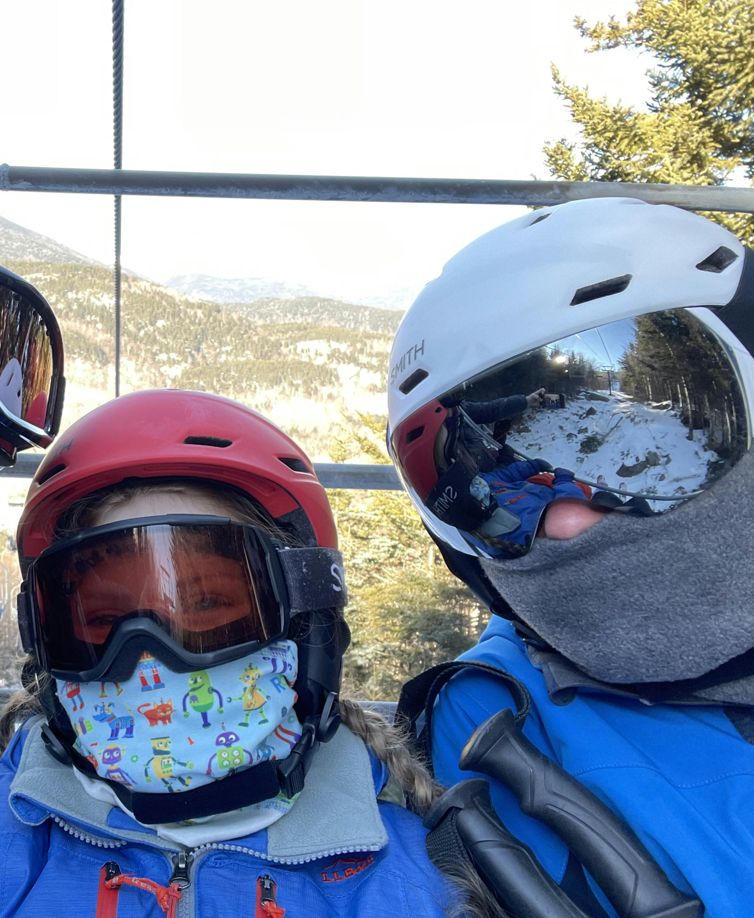 Two people on a ski lift. One is wearing the Smith Mission MIPS Helmet.