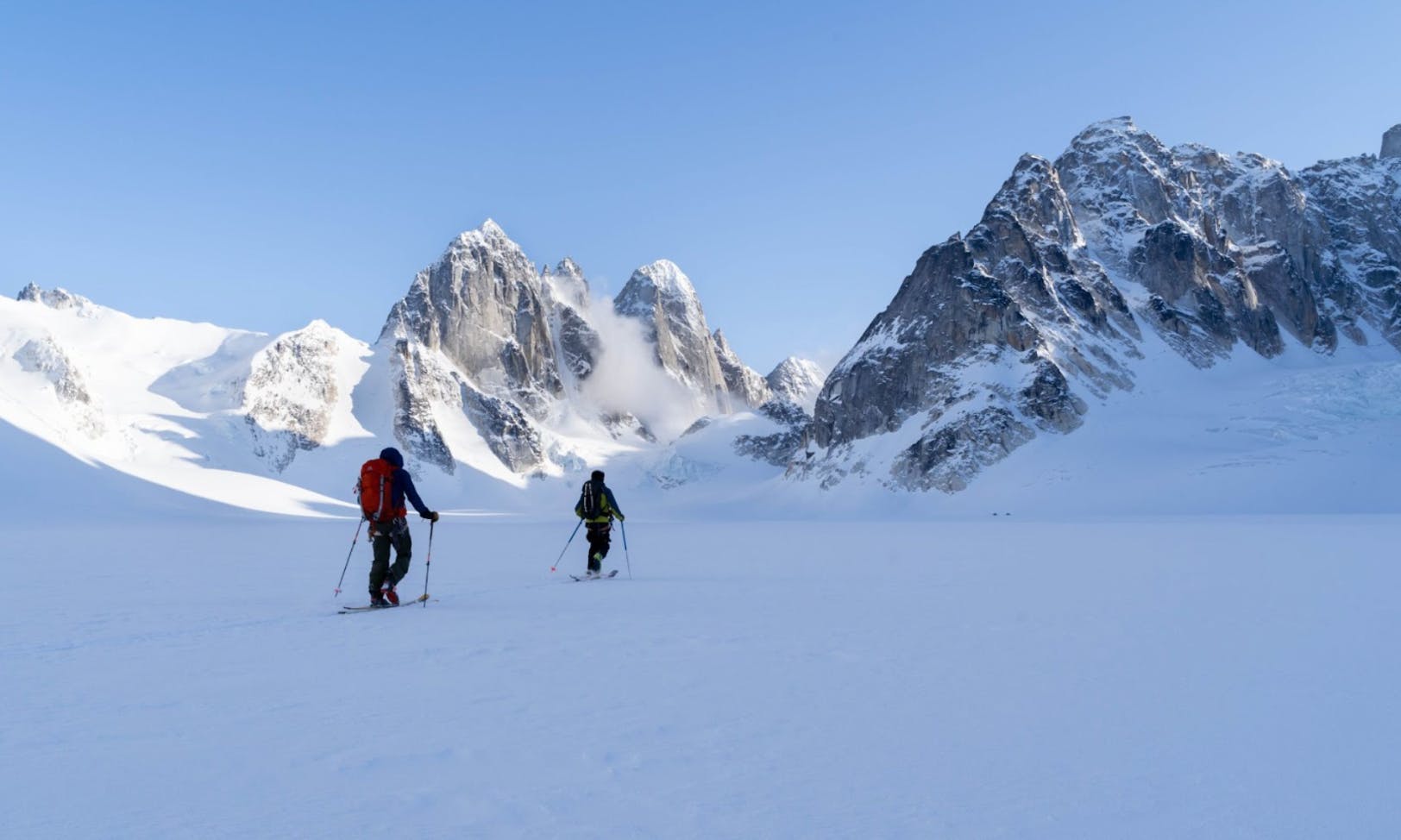 Two skiers walking up a snowy mountain. 