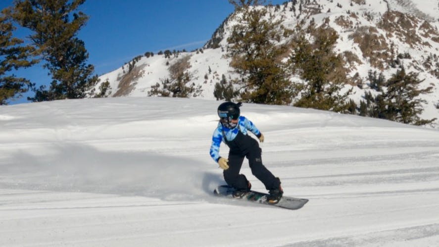 Snowboard Expert Arielle Busch riding the 2023 GNU Ladies Choice snowboard on a groomed run