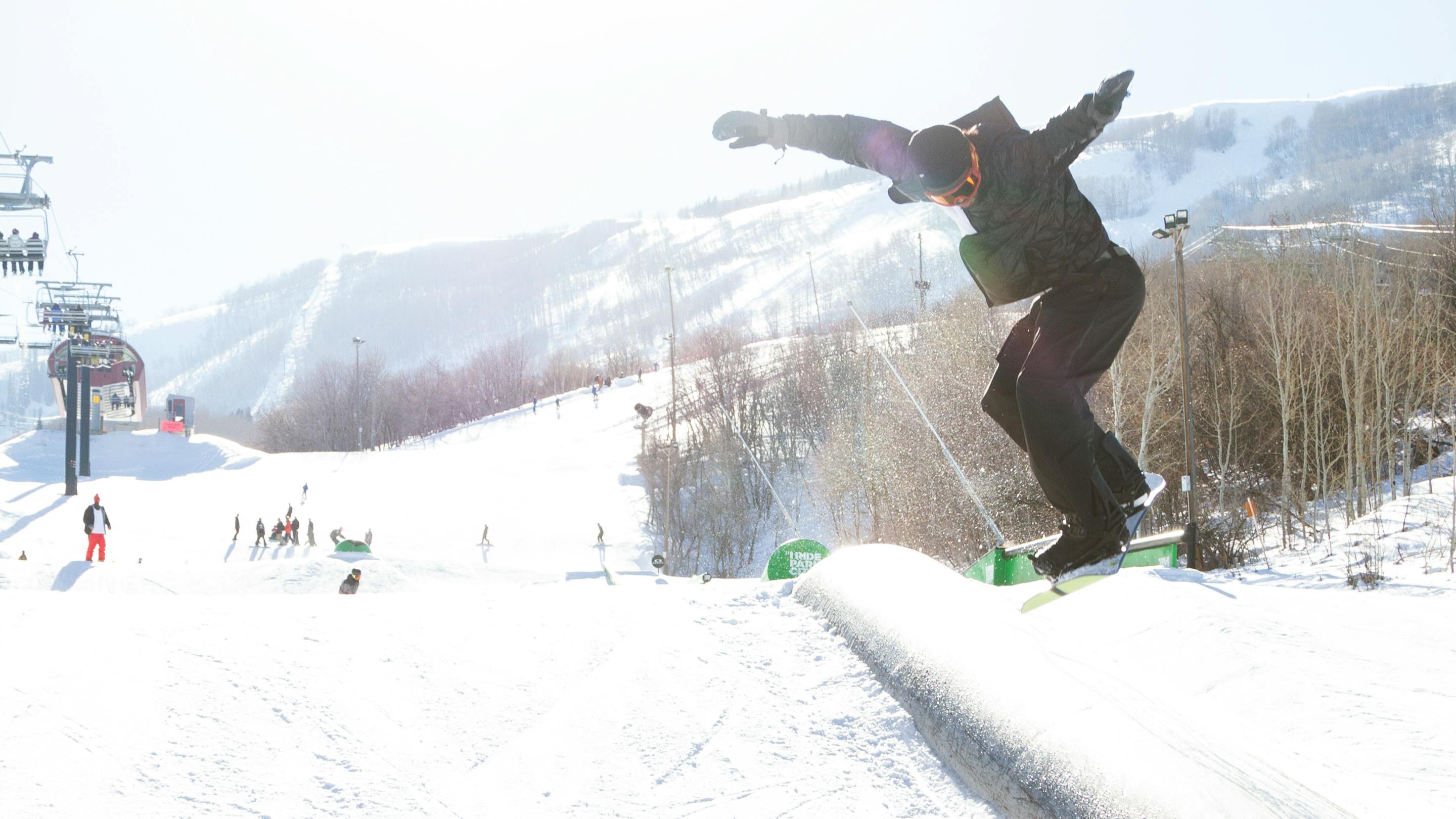 A snowboarder hits a feature in a park at a ski resort.