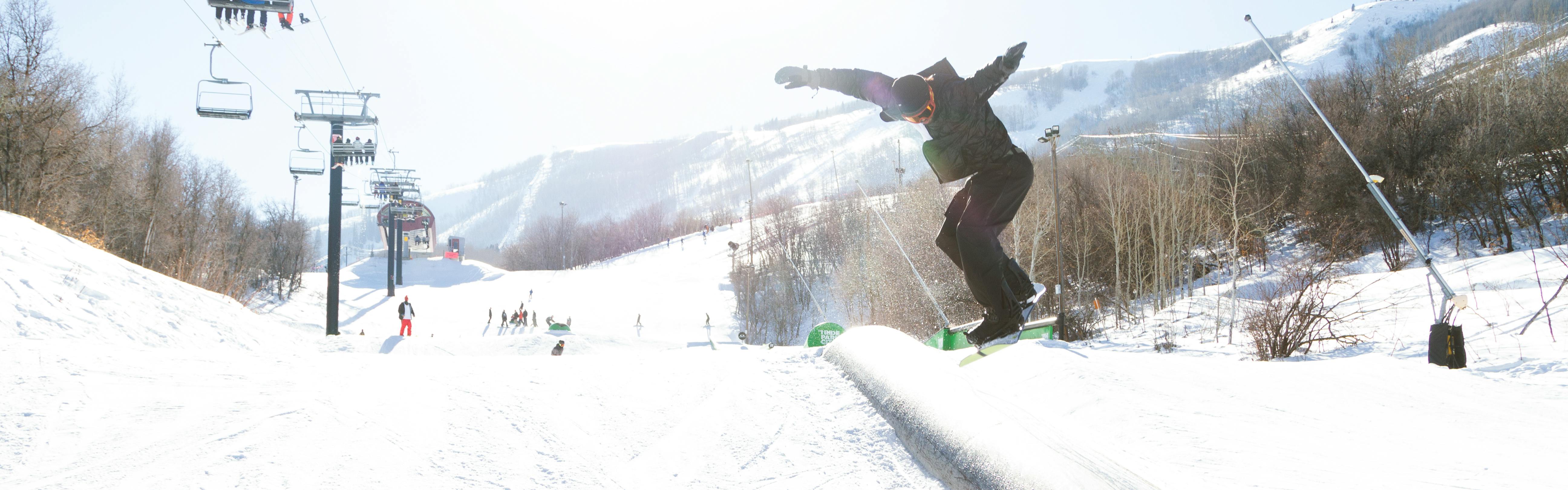 A snowboarder hits a feature in a park at a ski resort.