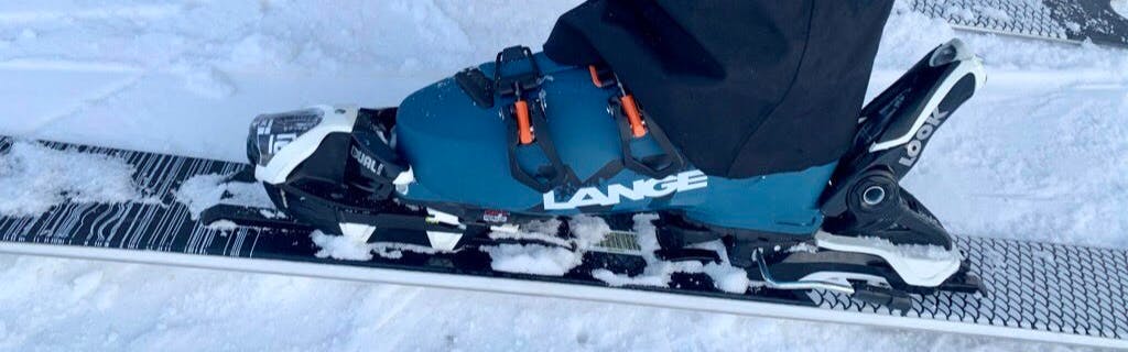 Picture of the boot locked in on skis in the snow.