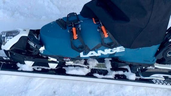 Picture of the boot locked in on skis in the snow.