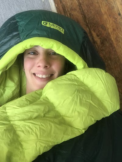 A woman smiling in the Nemo Disco 15 degree sleeping bag. 