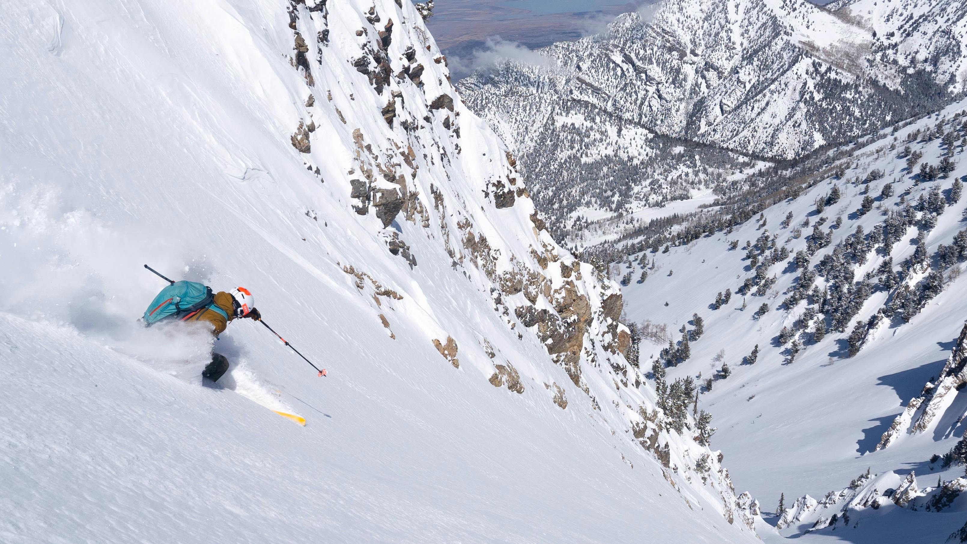 A skier turning down a steep, snowy mountain. 