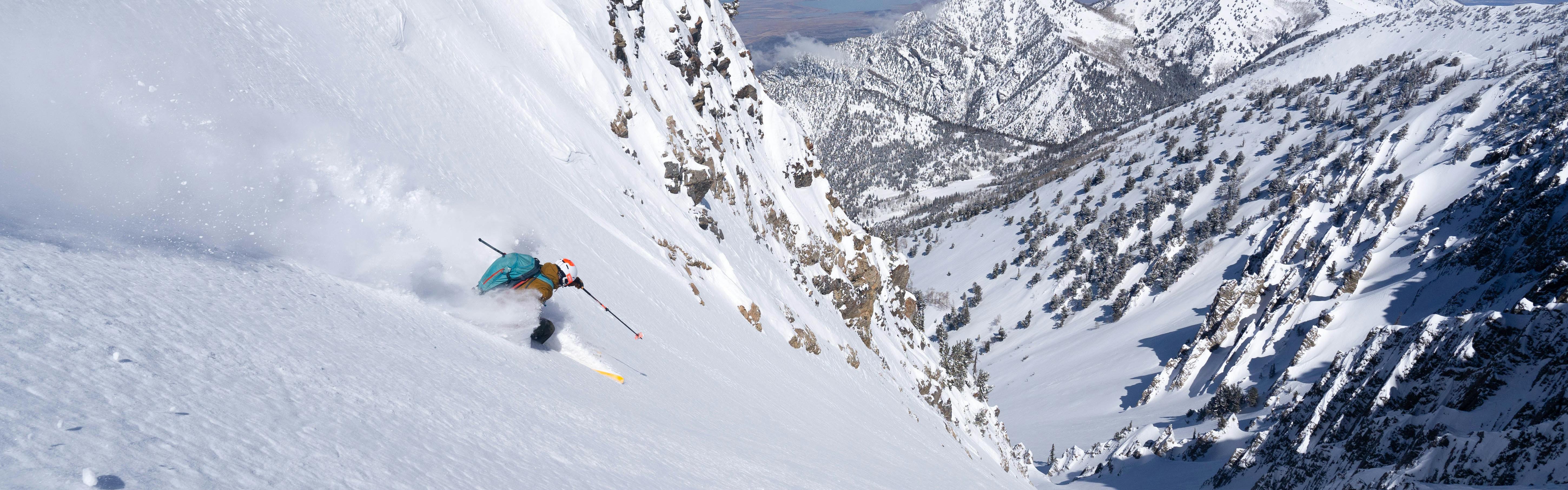 A skier turning down a steep, snowy mountain. 