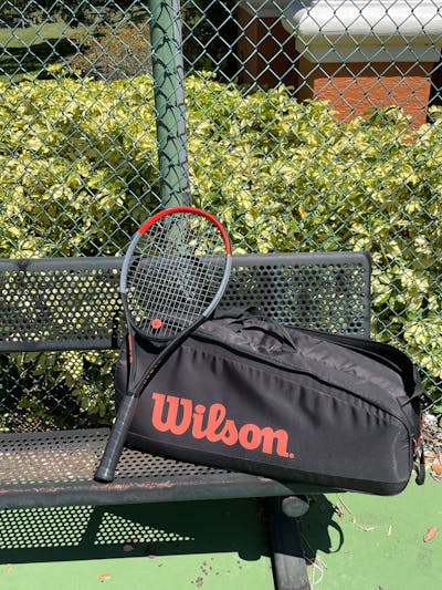 The Wilson Clash 100 Racquet sitting on a bench.