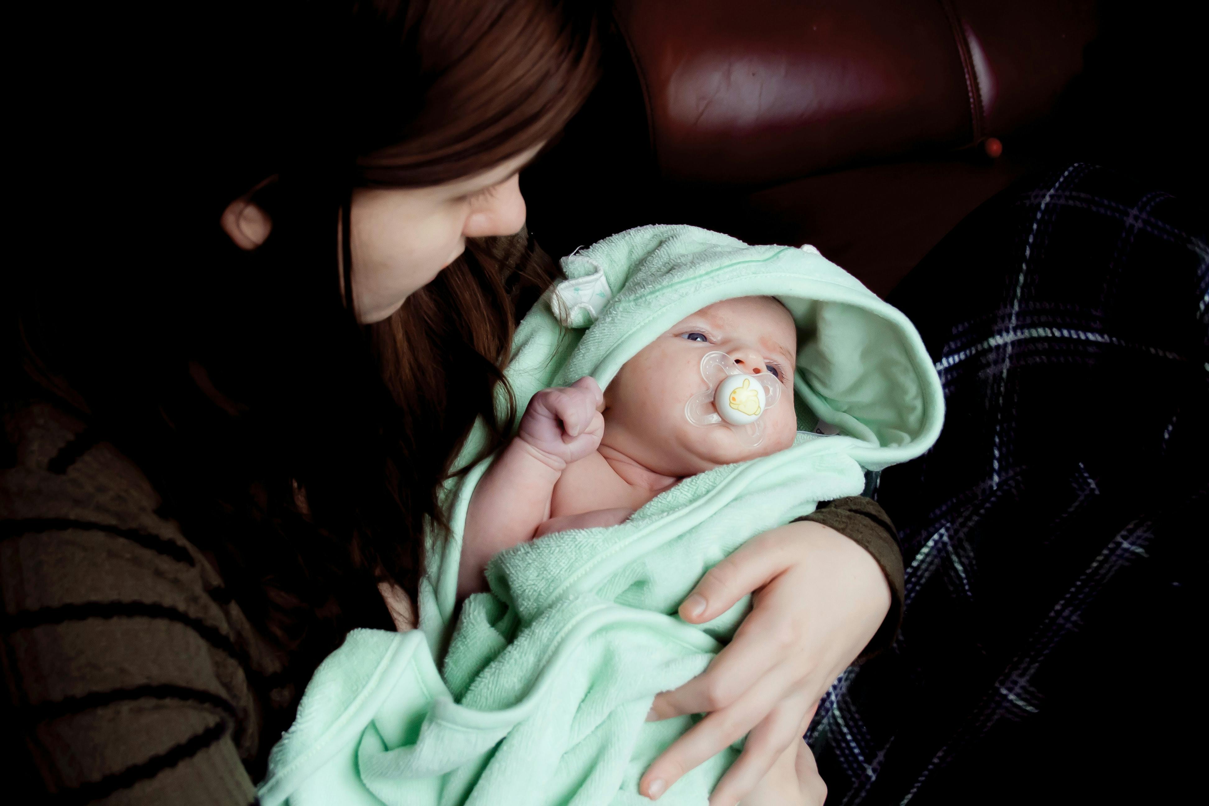 A mom holds a baby wrapped in a towel. 