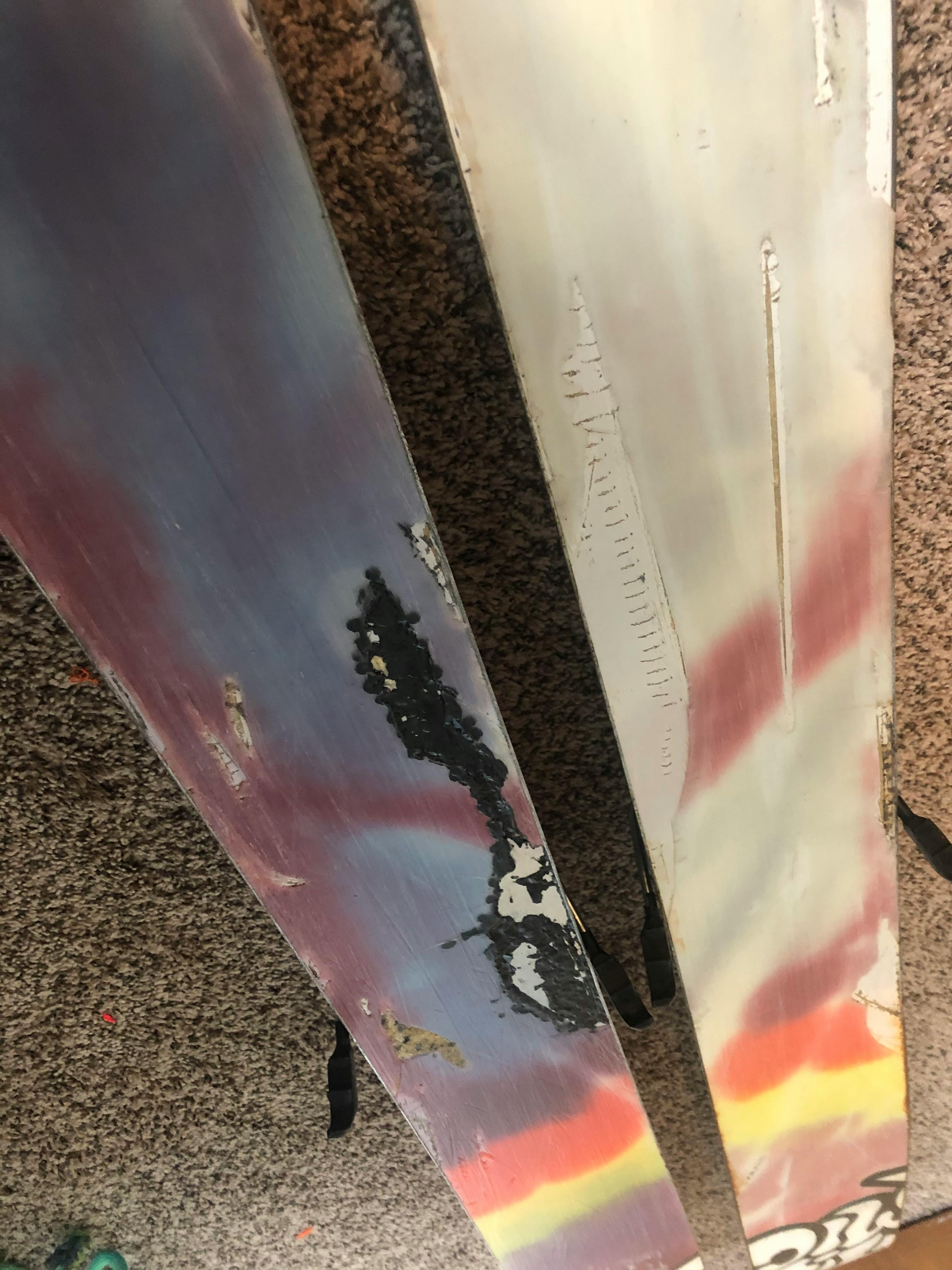 The bottom of a pair of skis - they are torn up from rocks