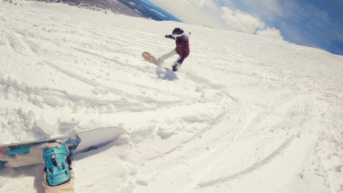 Two snowboarders going down a run together.