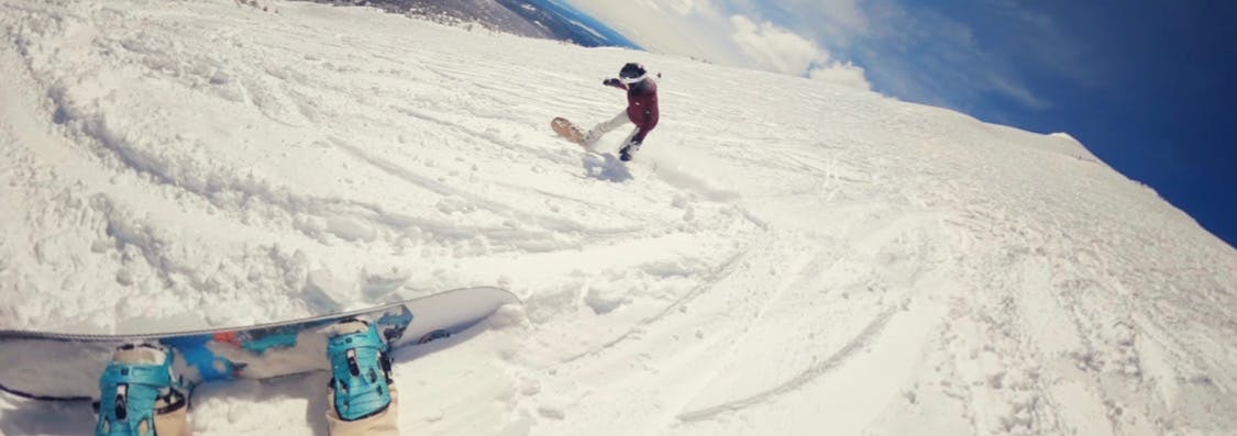 Two snowboarders going down a run together.