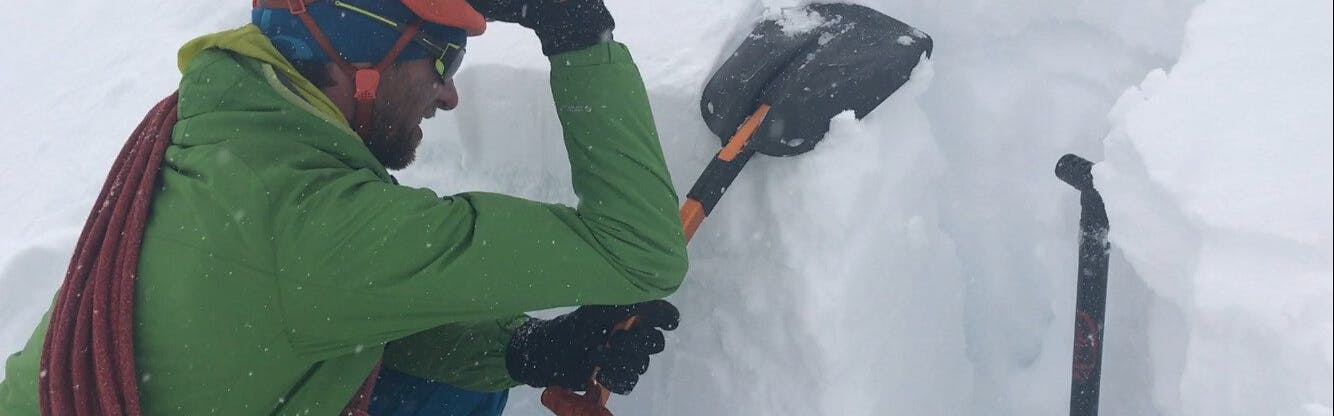 A man digs a snow pit with an avalanche shovel.