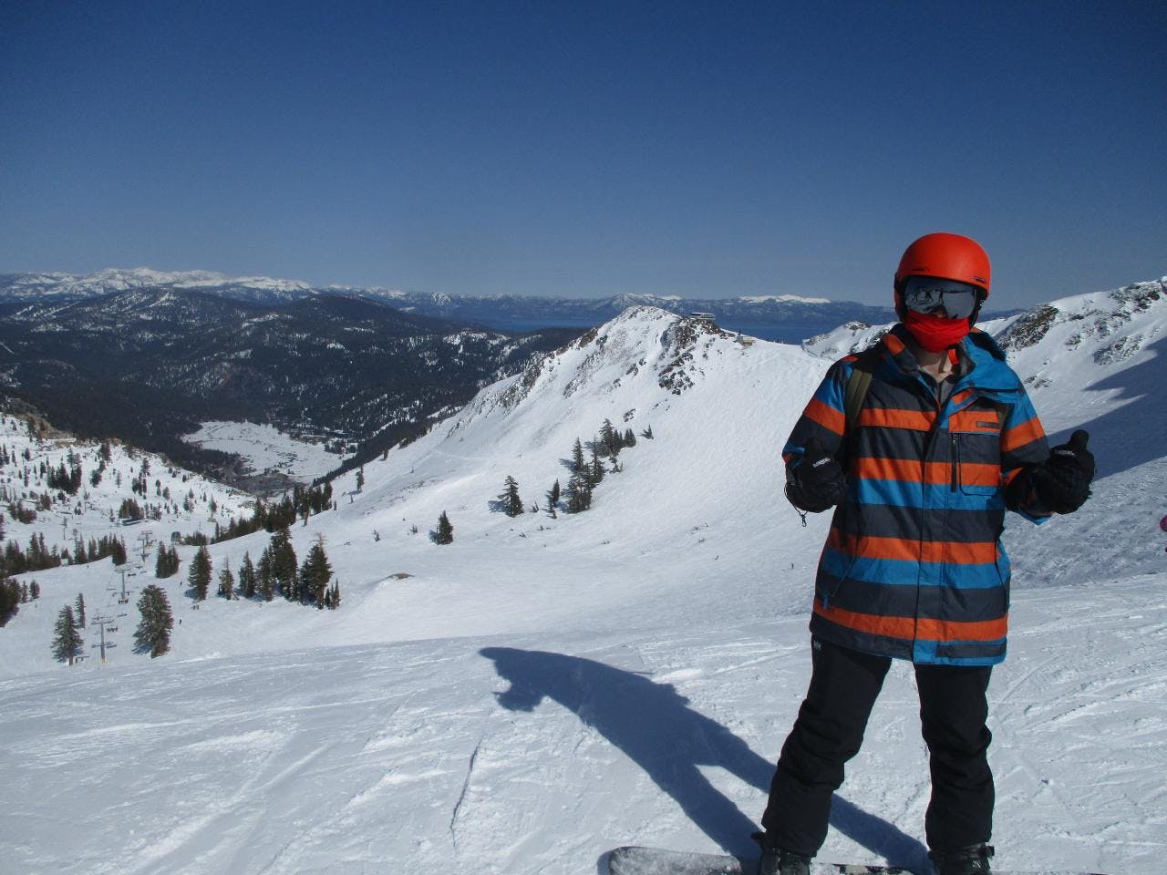 A snowboarder standing at the top of a snowy run. 