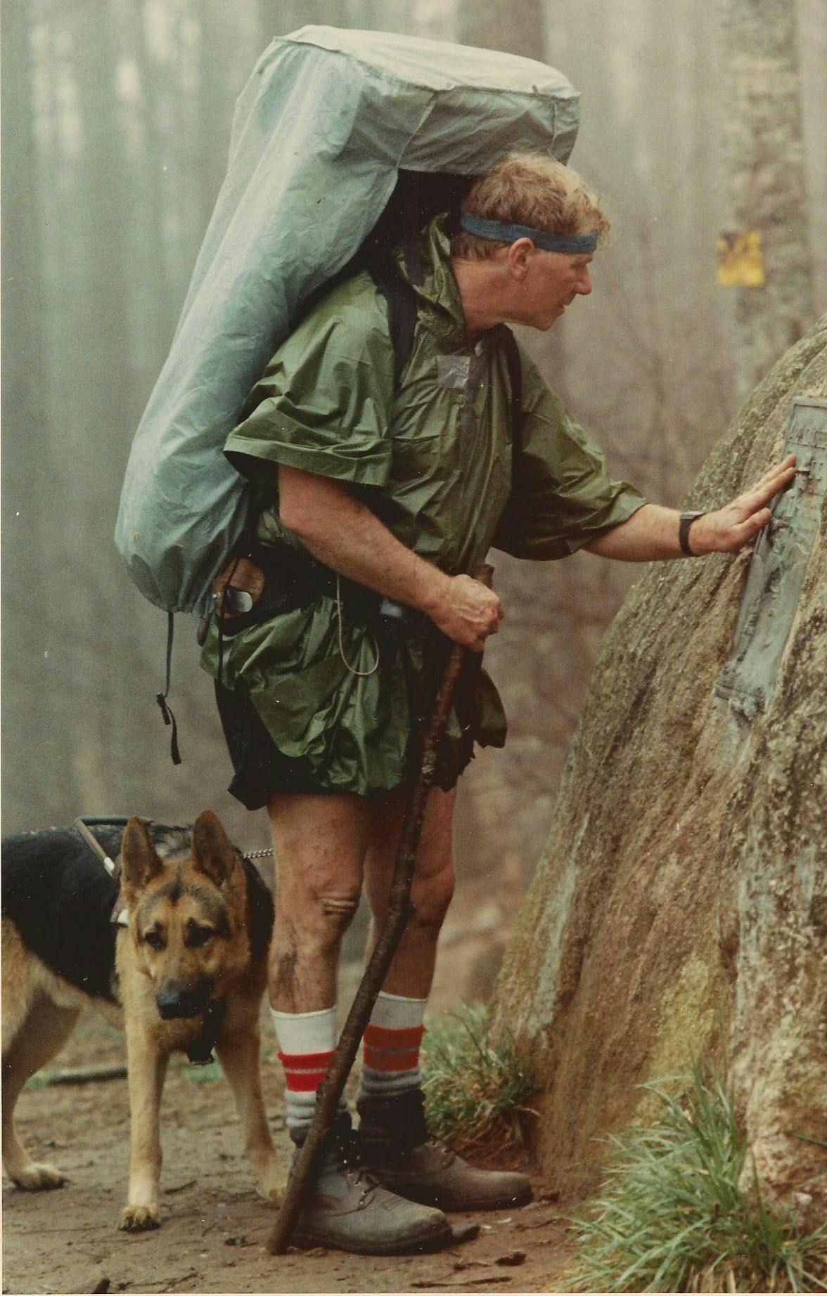An image of Bill Irwin with his dog, Orient, a German Shepherd. Irwin is wearing hiking gear and carrying a large pack.