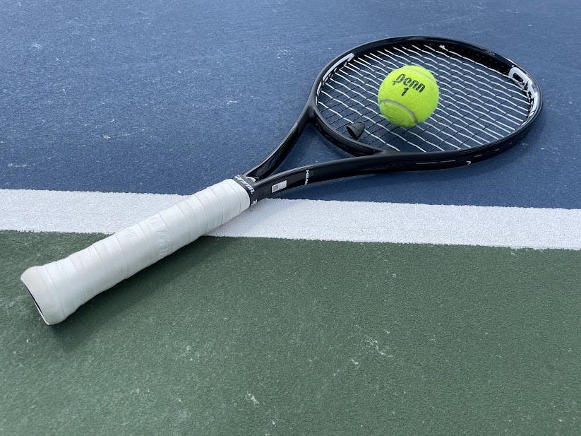 A tennis racquet laying on a court.