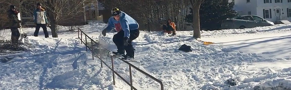 A snowboarder slides across a rail on his snowboard. 