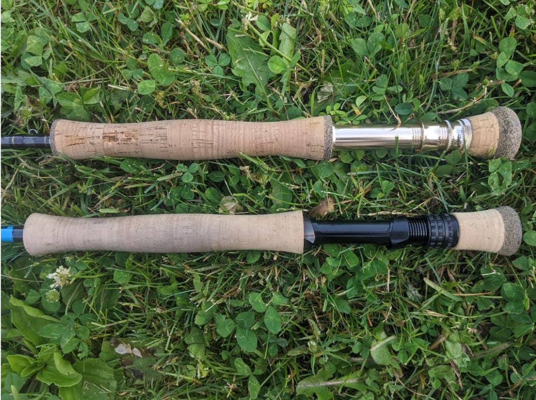 Two full wells cork grips with fighting butts sitting next to each other in the grass.