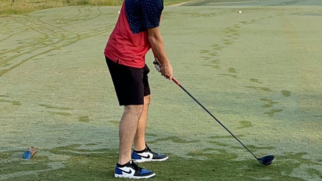 A golfer swinging at a ball with the  Srixon ZX5 Driver.