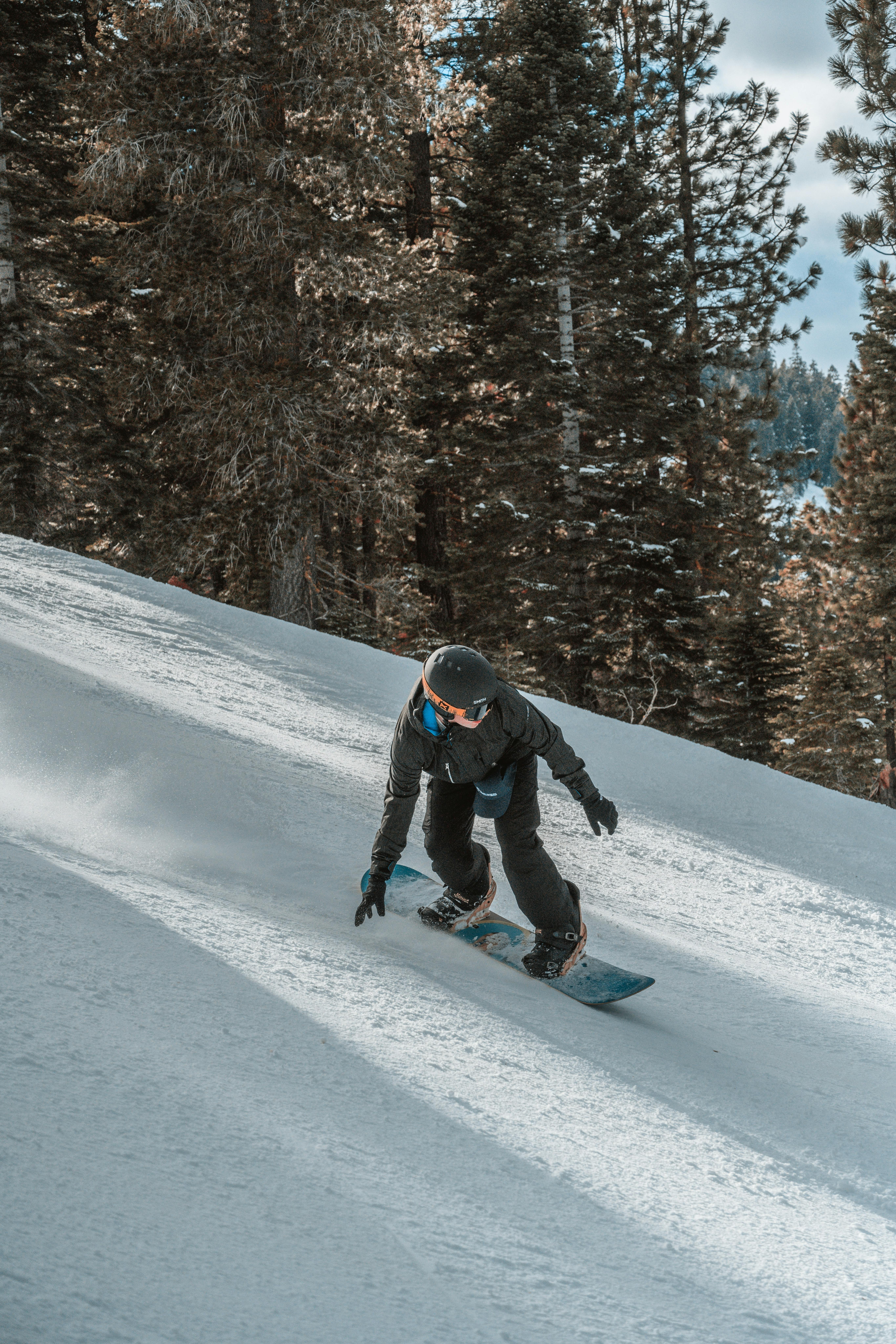 A snowboarder turns down a mountain. 