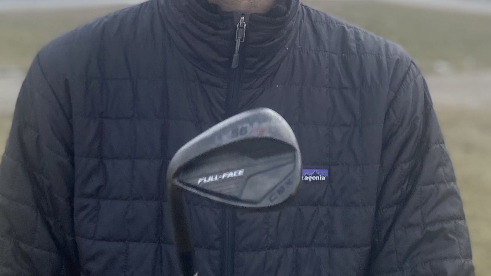 A man holding a Cleveland CBX Full-Face Wedge. 