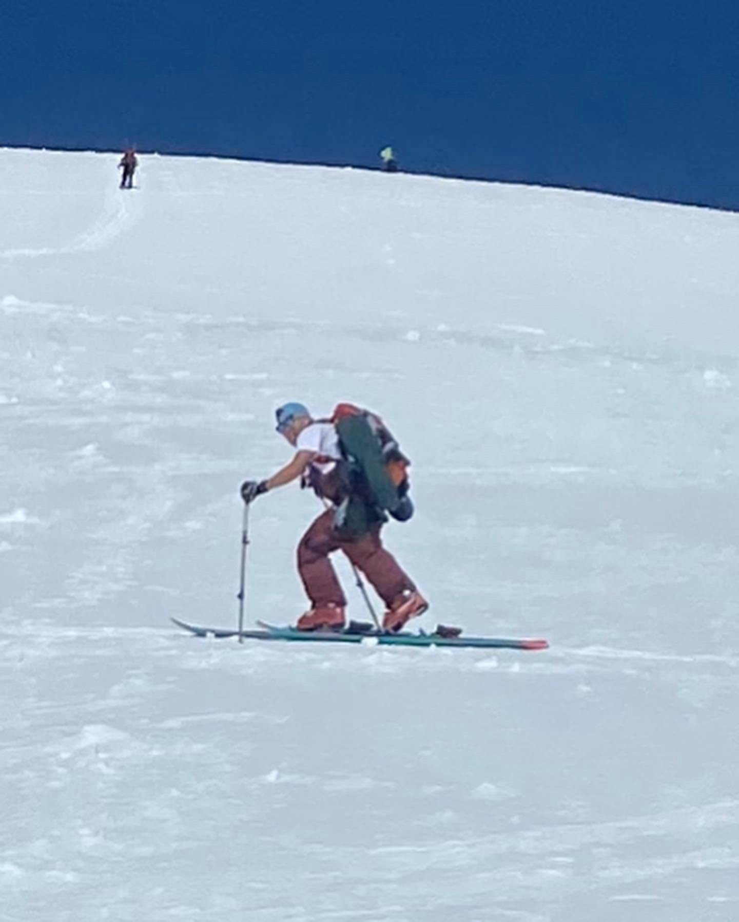 A skier walking uphill wearing the Flylow Baker Bib Pants.