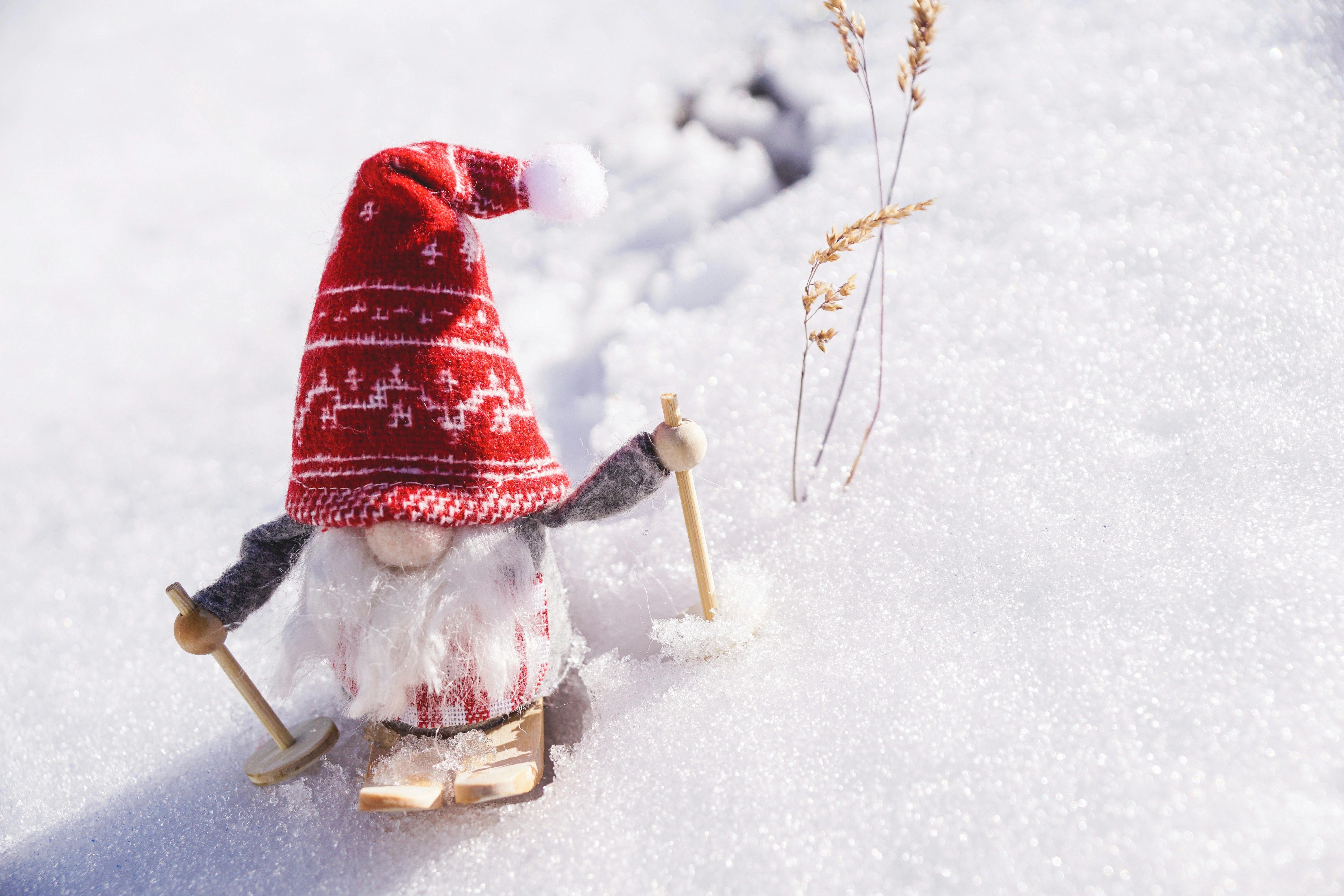 A small wooden gnome with a red hat on skis